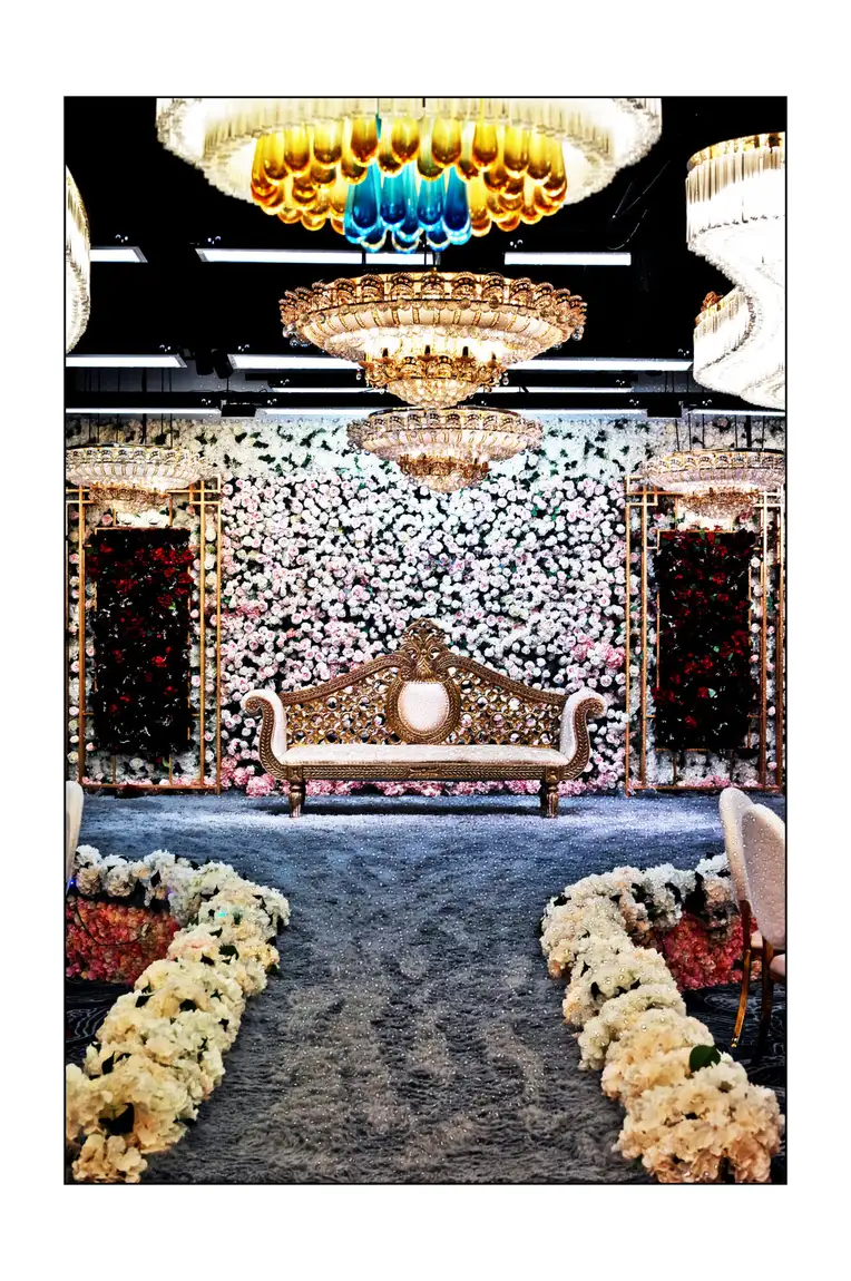 Floral pelamin and gold bridal dais in the ballroom